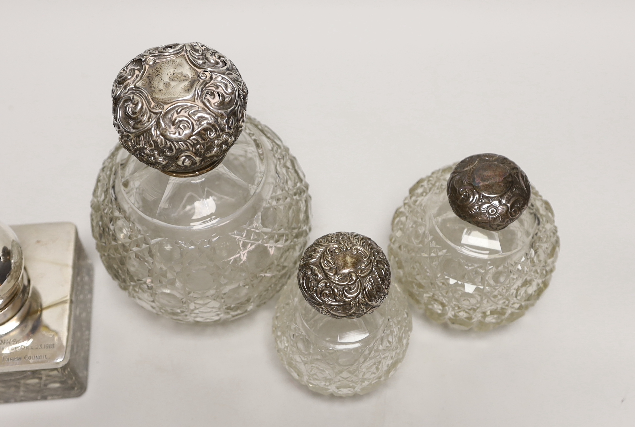 A George V silver mounted glass inkwell and three silver mounted cut glass scent bottles, largest 16cm (a.f.).